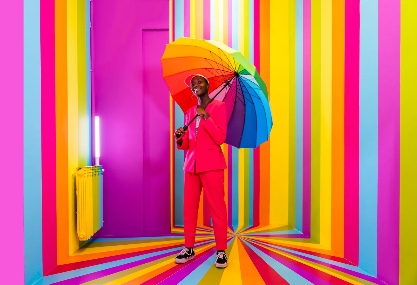 Person with a rainbow umbrella in a striped corridor